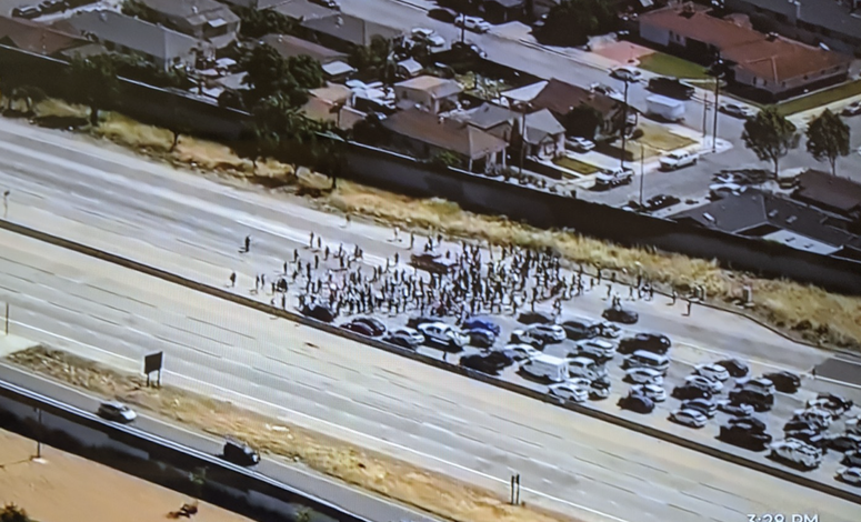 An overhead view of a protest on Highway 101 in San Jose, stopping traffic in both directions.